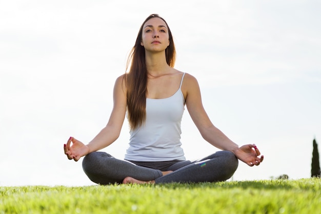 Bela jovem fazendo yoga na rua.