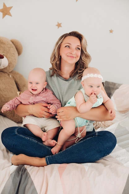 Bela jovem mãe sentada no chão com seus filhos e sorrindo