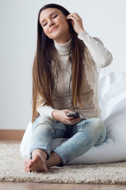 Bela jovem ouvindo música com telefone celular em ho