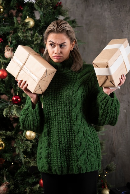 Bela jovem segurando uma caixa de presente perto de uma árvore de natal