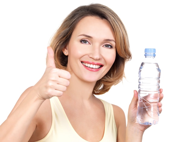 Bela jovem sorridente com uma garrafa de água em branco.