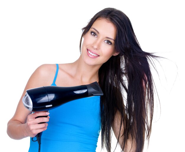 Bela jovem sorridente secando o cabelo com secador de cabelo - isolado no branco