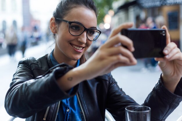 Bela jovem usando seu celular na rua.