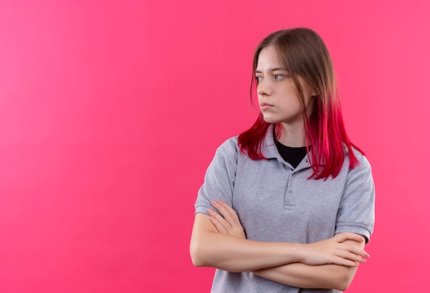 bela jovem vestindo uma camiseta cinza cruzando as mãos na parede rosa isolada com espaço de cópia