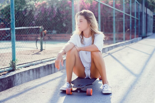 Bela moça sexy em calções com longboard em clima ensolarado