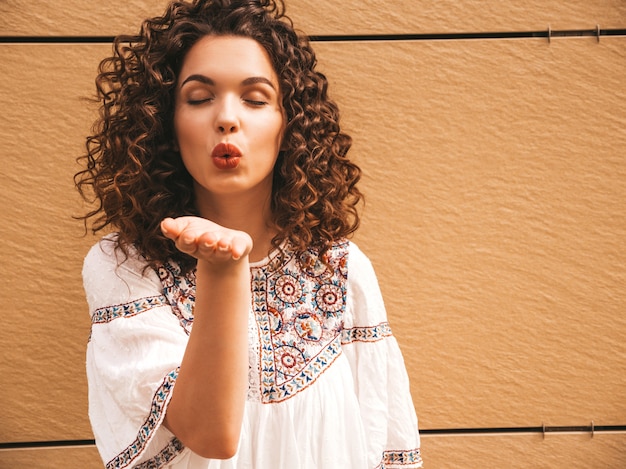 Foto grátis bela modelo sorridente com afro cachos penteado vestido com vestido branco hipster de verão.