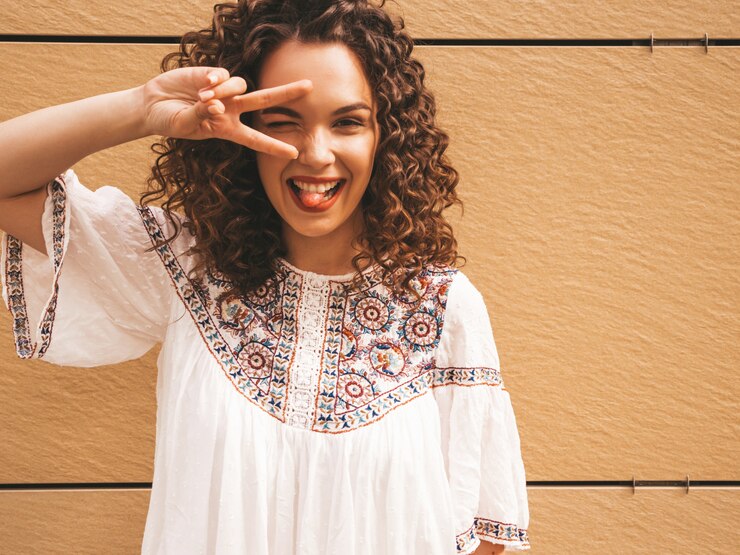 Foto grátis bela modelo sorridente com afro cachos penteado vestido com vestido branco hipster de verão.