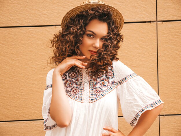 Bela modelo sorridente com afro cachos penteado vestido com vestido branco hipster de verão.