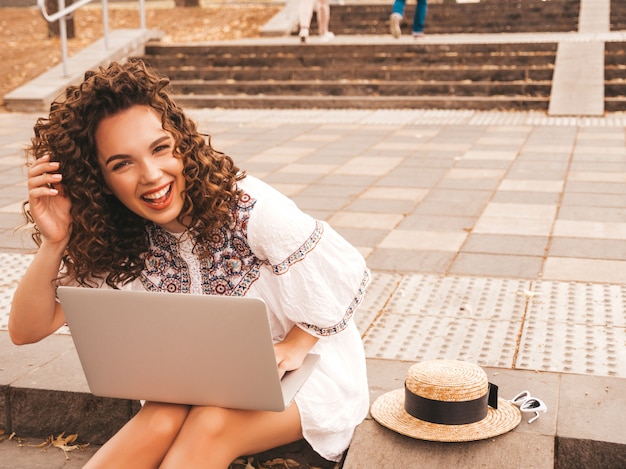 Foto grátis bela modelo sorridente com afro cachos penteado vestido com vestido branco hipster de verão.