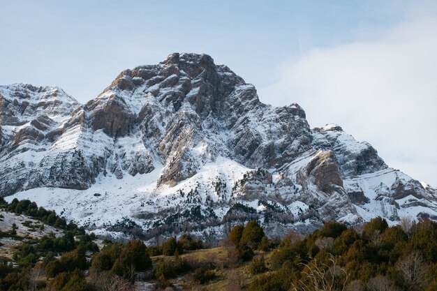 Bela montanha rochosa coberta de neve sob um céu nublado