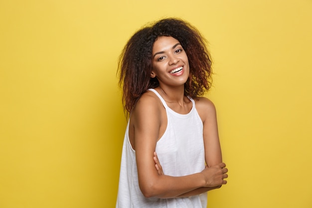 Bela mulher afro-americana atraente com óculos na moda postagem sobre o fundo amarelo do estúdio. Espaço de cópia.