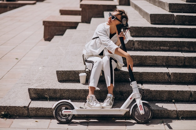 Bela mulher sentada na escada com sua scooter