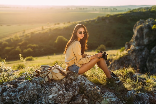 Foto grátis bela mulher sentada na rocha segurando binocular