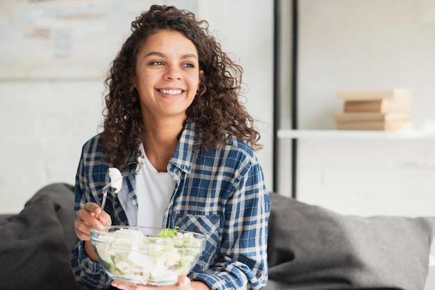 Bela mulher sorridente comendo salada