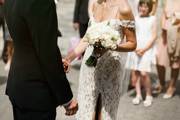 Bela noiva jovem e sexual com um vestido branco e um noivo bonito, nos abraçam.