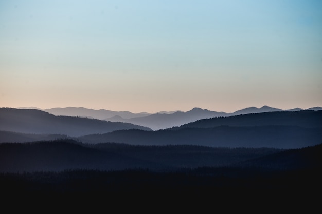 Bela paisagem com montanhas e colinas sob um céu rosado