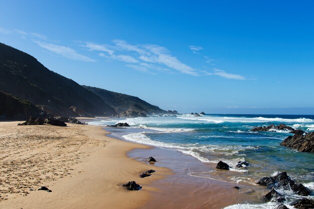 Bela paisagem de praia cercada por morros e céu claro