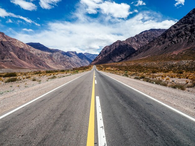 Bela paisagem de um caminho cercado por altas montanhas rochosas sob um céu nublado