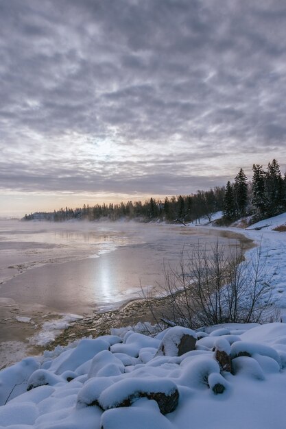 Bela paisagem de um lago rodeado por altas montanhas rochosas cobertas de neve sob o sol