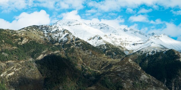 Bela paisagem de uma alta cordilheira rochosa coberta de neve sob um céu nublado