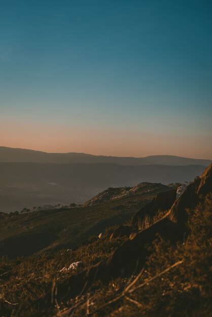 Foto grátis bela paisagem do pôr do sol sobre uma paisagem verde com montanhas rochosas