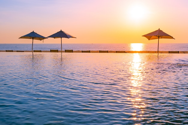 Foto grátis bela paisagem piscina exterior com guarda-chuva e espreguiçadeira no hotel resort para relax tra