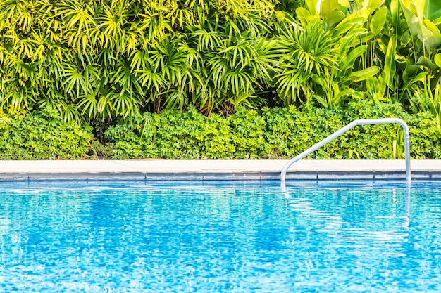 Bela piscina ao ar livre com cama espreguiçadeira e guarda-chuva no resort para viagens e férias