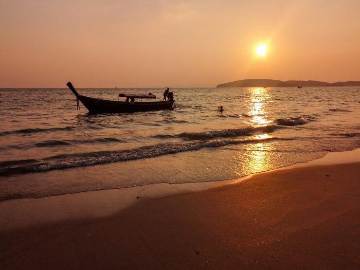 Bela praia com barco na água durante o pôr do sol
