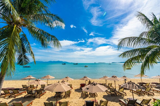 Bela praia tropical mar e oceano com coqueiro e guarda-chuva e cadeira no céu azul