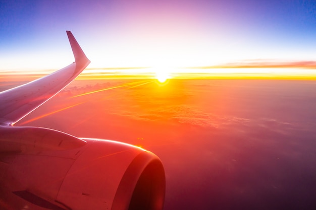 Bela vista aérea da asa de avião na nuvem branca e céu ao pôr do sol