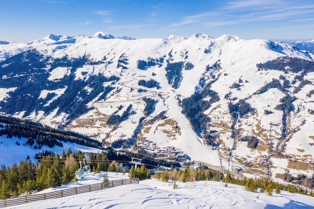 Bela vista aérea de uma estação de esqui e uma vila em uma paisagem montanhosa, nos Alpes