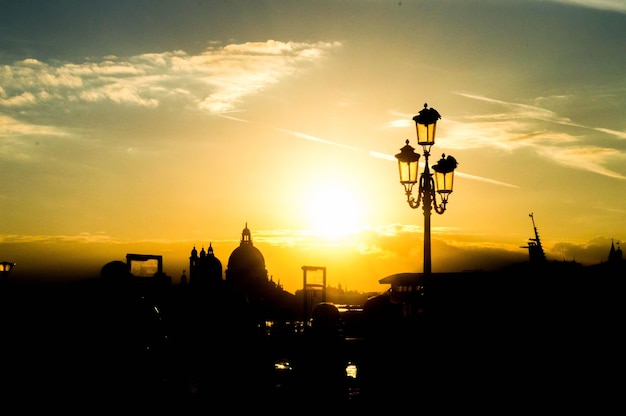 Bela vista da cidade com silhuetas de um poste de luz e edifícios ao pôr do sol