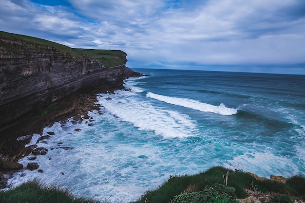 Bela vista da onda de espuma na costa perto do penhasco