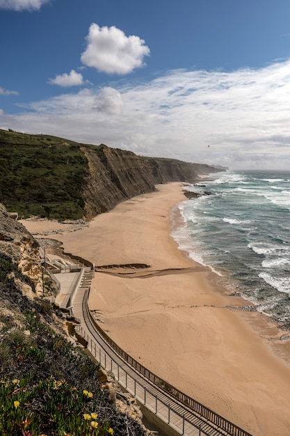 Bela vista da praia arenosa com um caminho na falésia