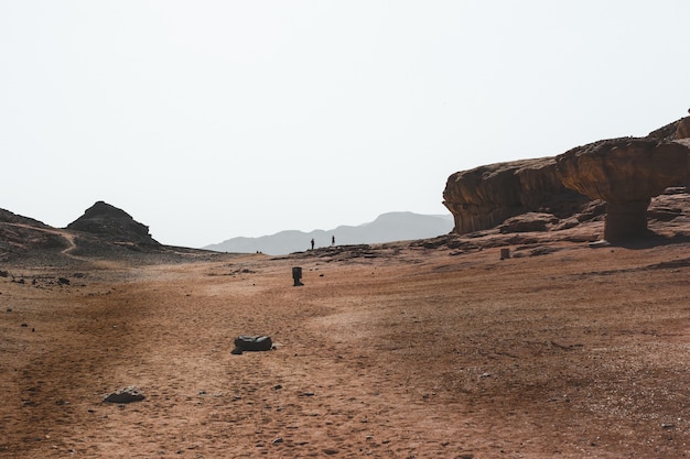 Bela vista das grandes rochas e dunas em um deserto com as montanhas ao fundo