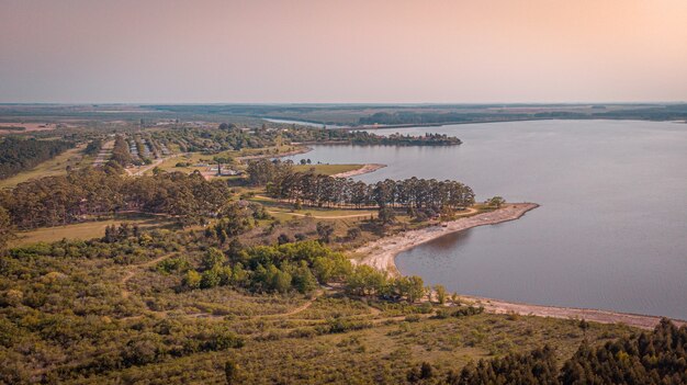 Bela vista de árvores perto de um lago tranquilo sob um fundo de pôr do sol