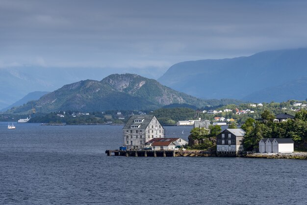 Bela vista de edifícios na costa perto de Alesund, Noruega com altas montanhas