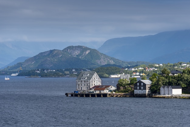 Bela vista de edifícios na costa perto de Alesund, Noruega com altas montanhas