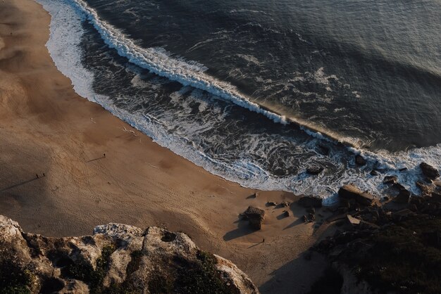 Bela vista de grandes ondas quebrando em uma praia ao pôr do sol