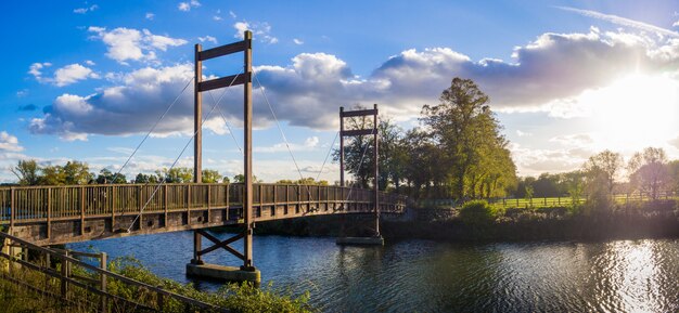 Belas árvores no parque com uma ponte sobre o rio ao pôr do sol em Windsor, Inglaterra