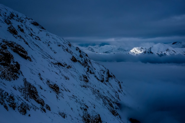 Belas montanhas e montanhas nevadas à noite com céu nublado de tirar o fôlego