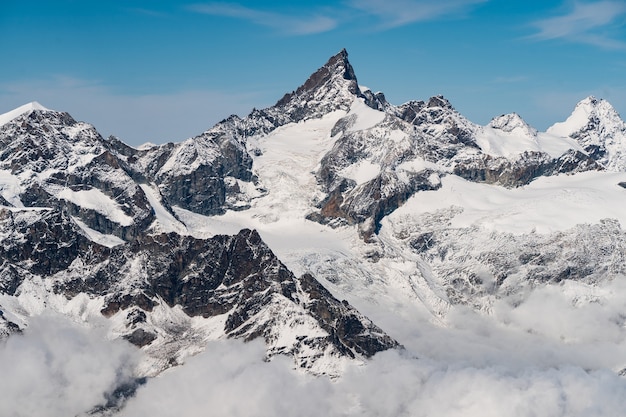 Belas paisagens de altas montanhas rochosas cobertas de neve sob um céu azul claro na Suíça