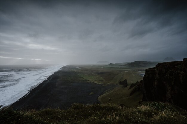 Belas paisagens do mar cercado por formações rochosas envoltas em névoa na Islândia