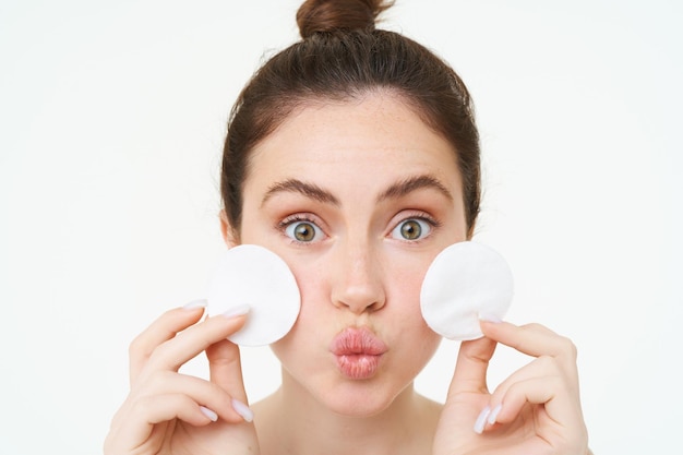 Foto grátis beleza e conceito feminino retrato em close-up jovem mulher segurando almofadas cosméticas de algodão perto de seu rosto