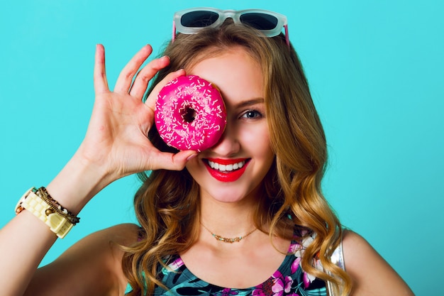 Foto grátis beleza loira moda modelo garota tomando rosquinhas rosa coloridas. mulher alegre engraçada com doces, sobremesa. dieta, conceito de dieta. comida não saudável. cores brilhantes.