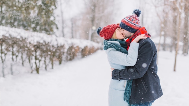 Belo casal se beijando na queda de neve