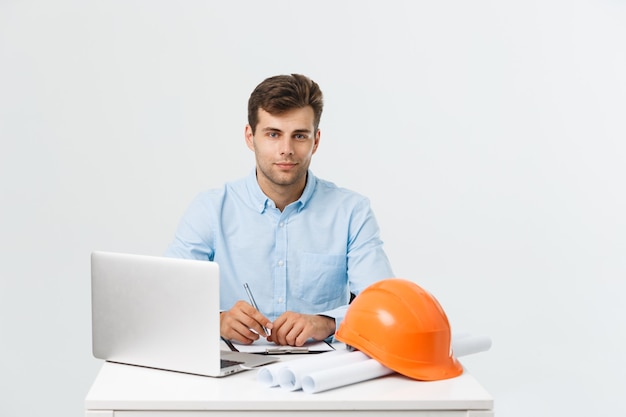 Foto grátis belo engenheiro civil trabalhando no escritório com um laptop