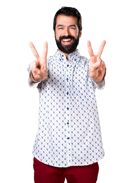 Foto grátis belo homem moreno com barba fazendo um gesto de vitória