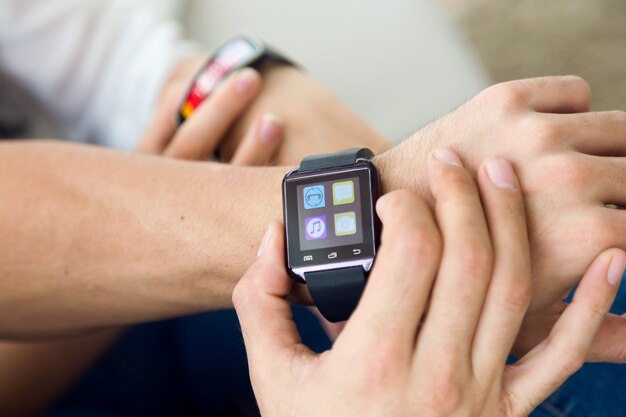 Belo jovem casal usando um smartwatch em casa.