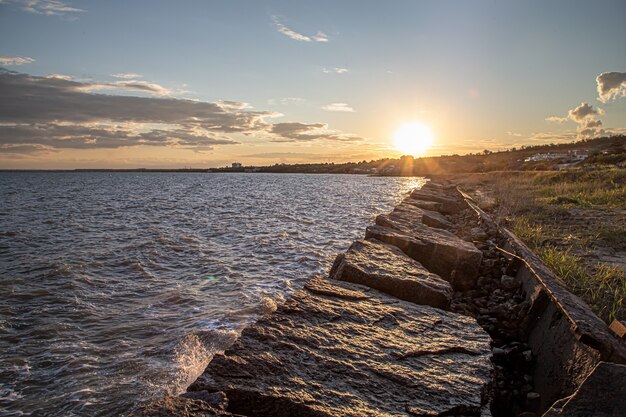 Belo mar ao pôr do sol perto da costa rochosa. Composição da natureza